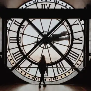 A woman standing in front of a clock.