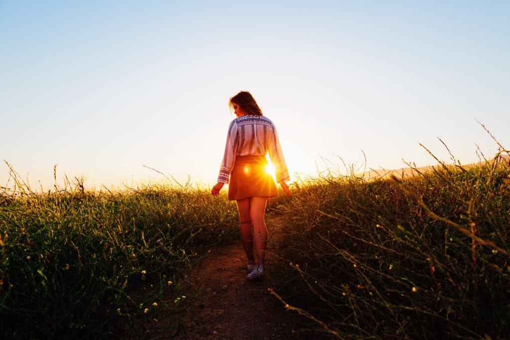 A woman walking in the grass during sunset
