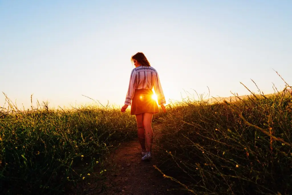 A woman walking in the grass during sunset
