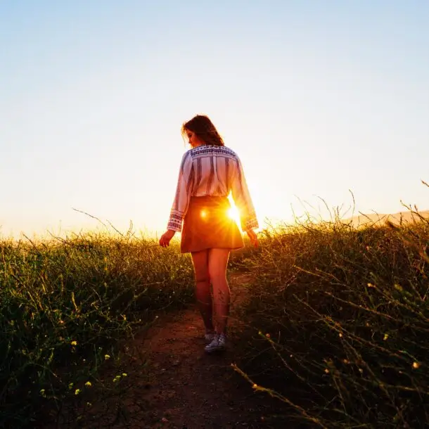 A woman walking in the grass during sunset