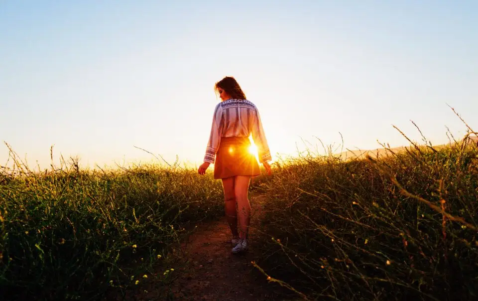 A woman walking in the grass during sunset
