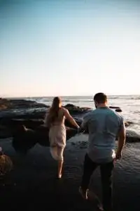 A woman and a man walking at night holding hands.
