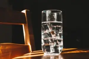 A cup of water with ice sitting on the table.