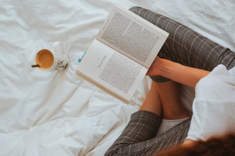 A woman reading a book on the bed.