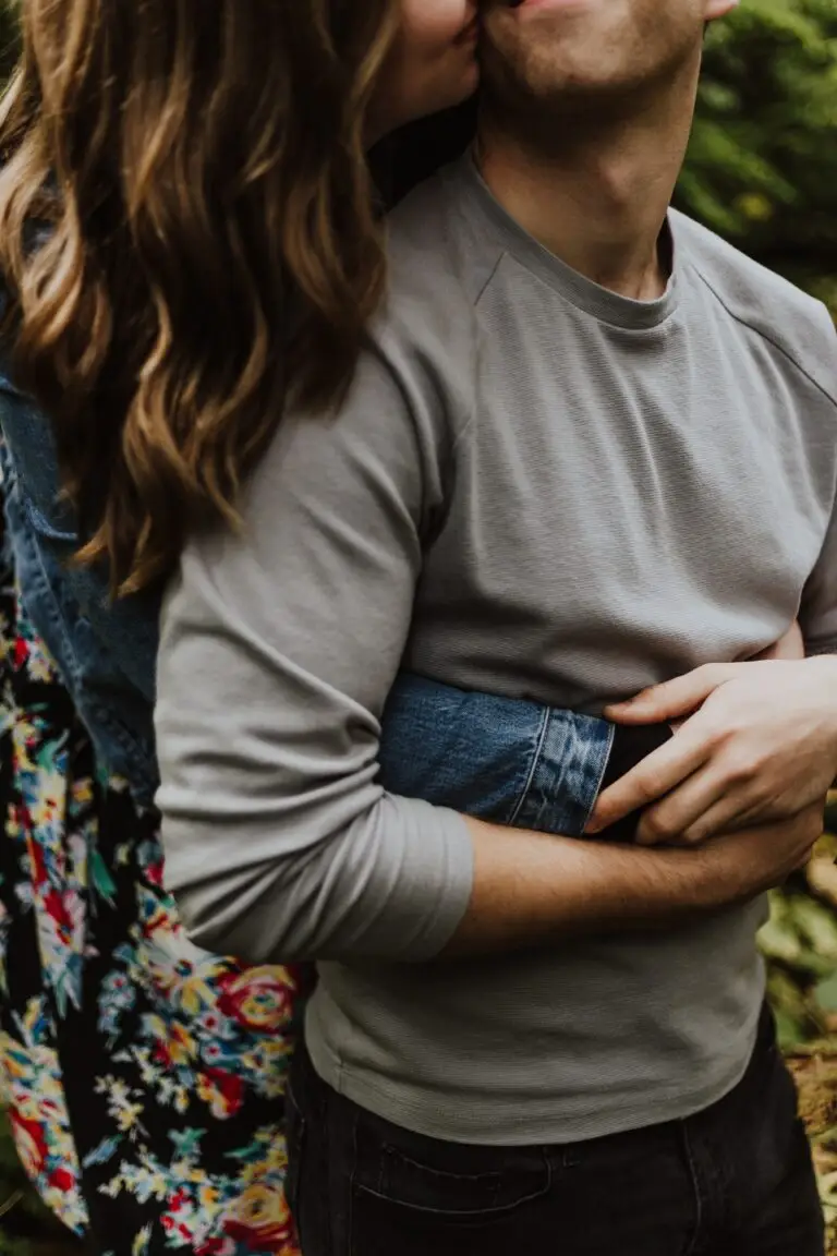 A woman hugging a man from behind.