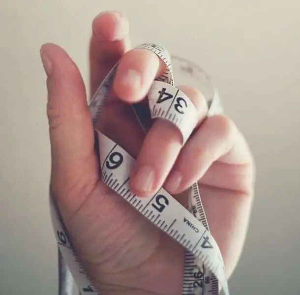 how to lose weight with hypothyroidismclose up of measuring tape wrapped around a hand