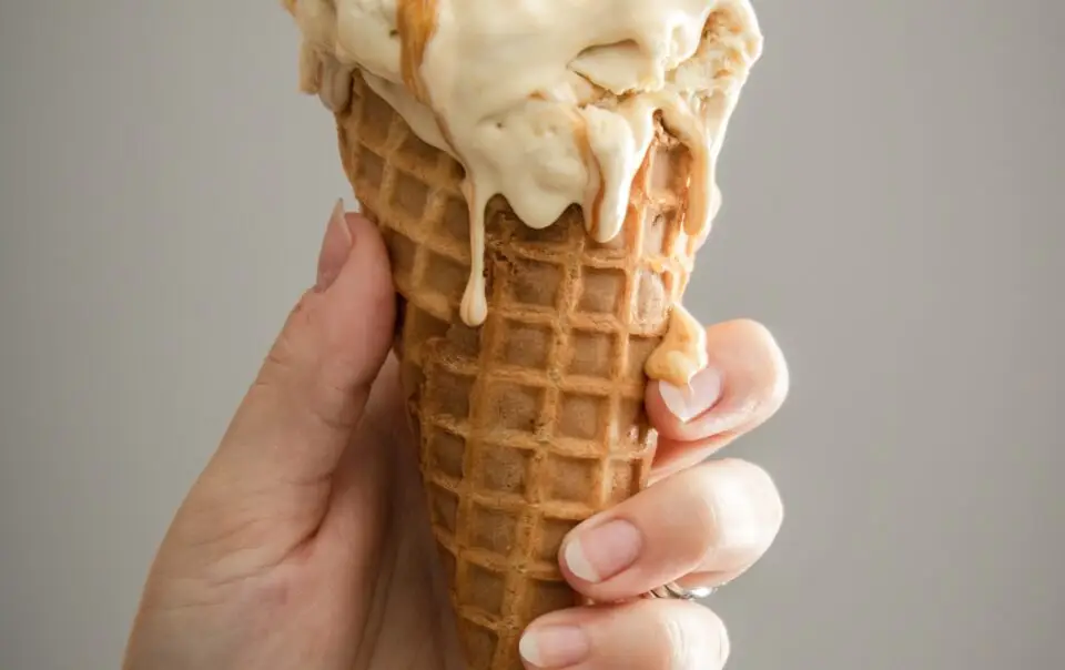 A person holding a vanilla ice cream.
