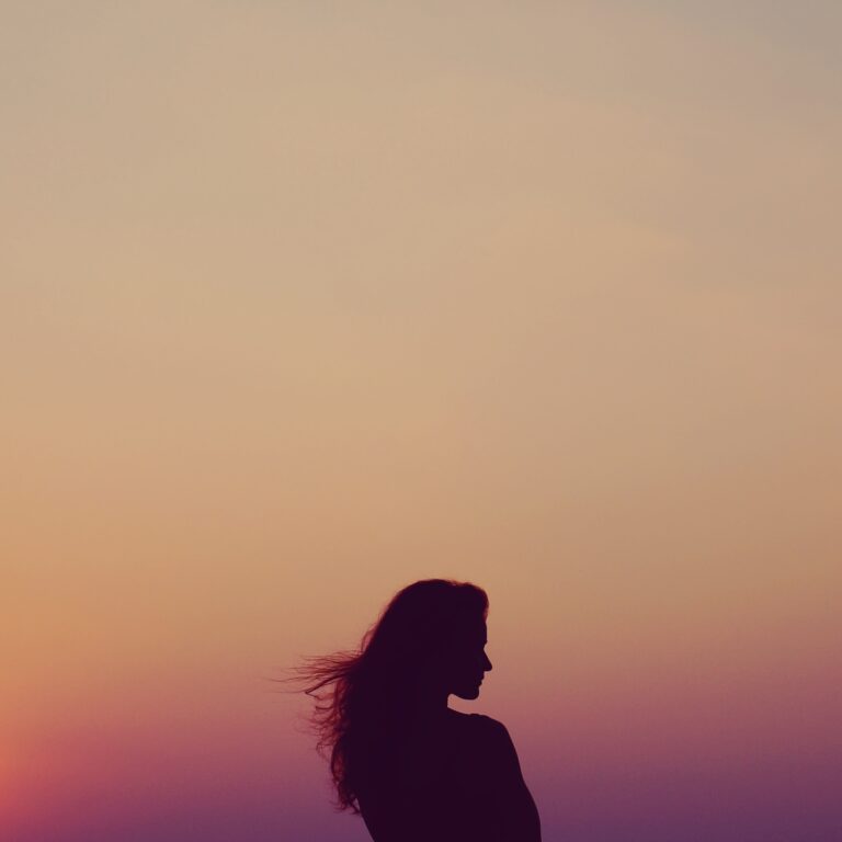 A woman looking to the right with a sunset in the background.