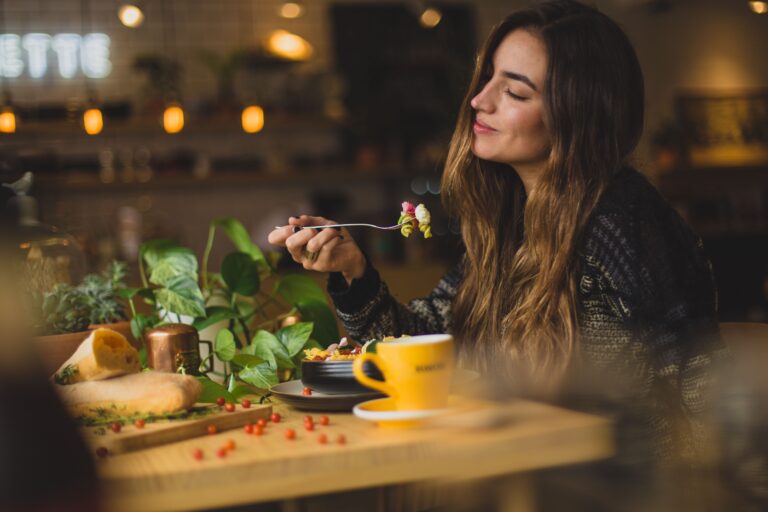 A woman sitting at a wood table eating a salad.
