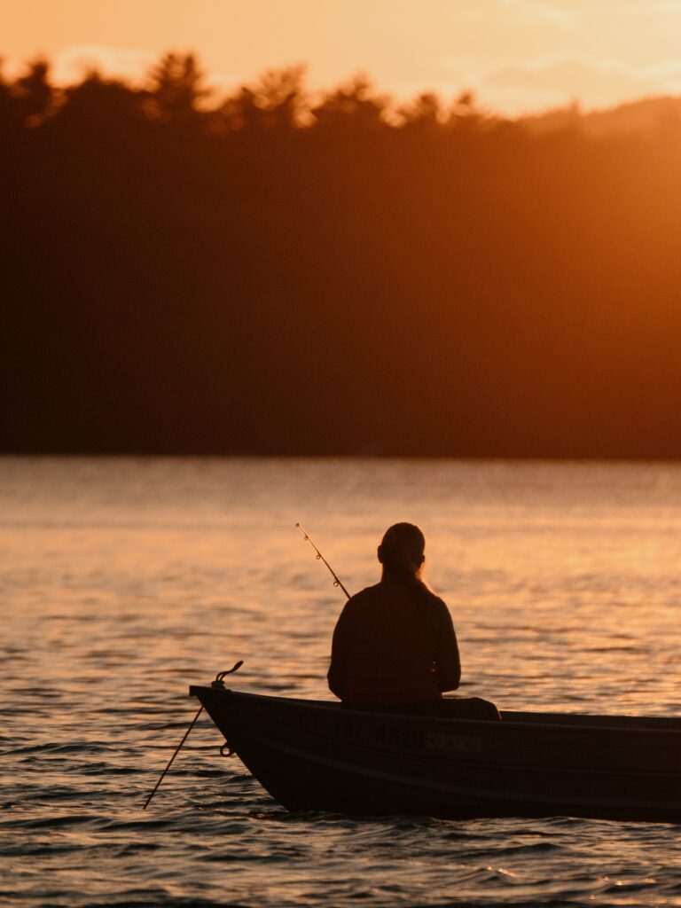 A person in a boat on the lake fishing.